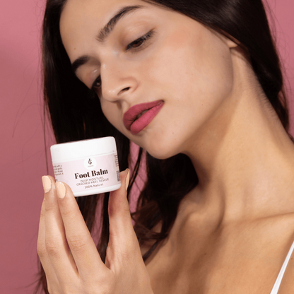 Woman holding a jar of foot balm against a pink background